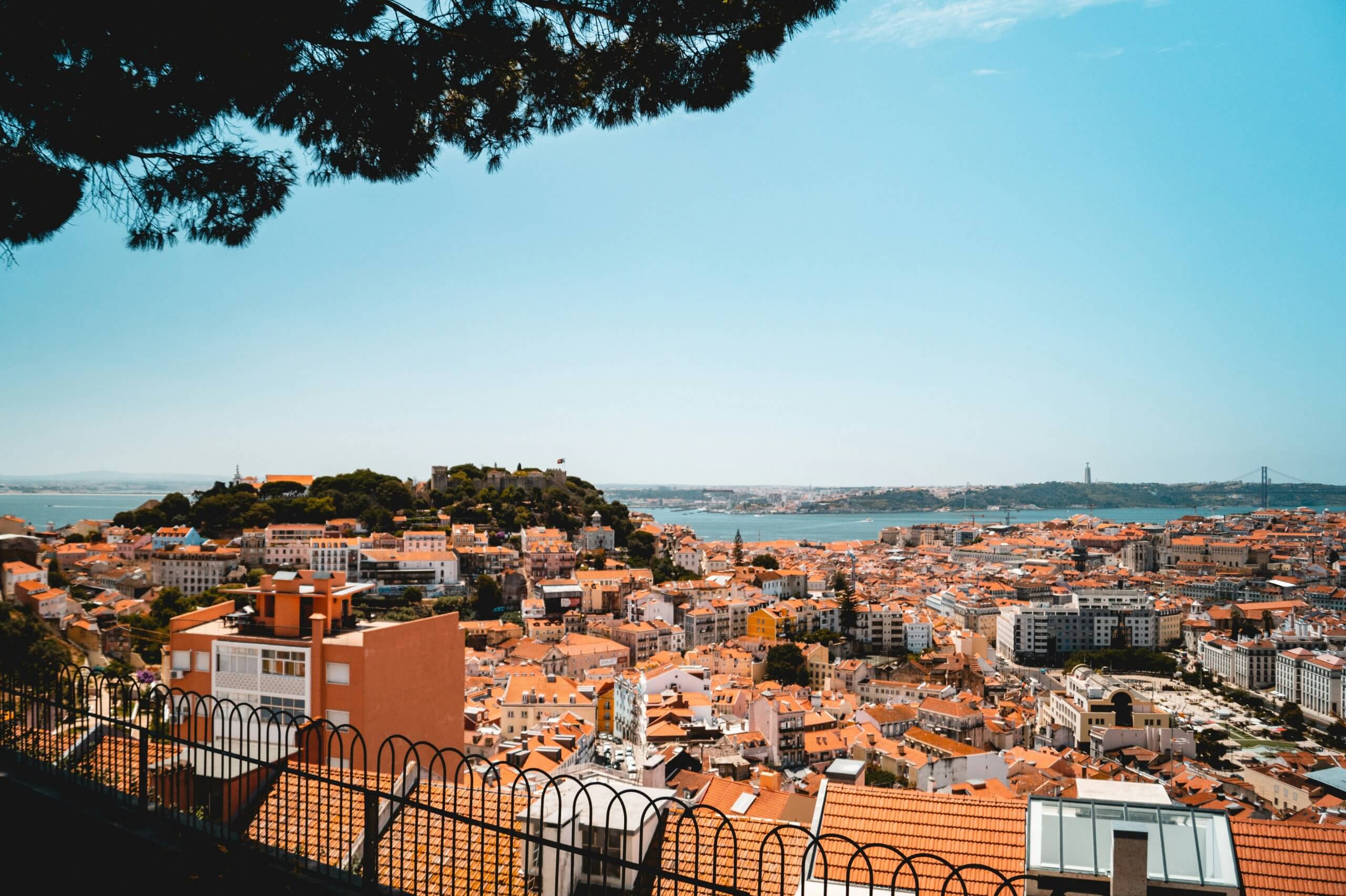 View across the terracotta rooftops of Alfama and the Tagus River from Miradouro de Santa Luzia in Lisbon